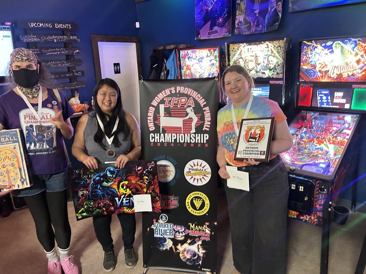The top three finishers with medals and prizes in front of the championship banner